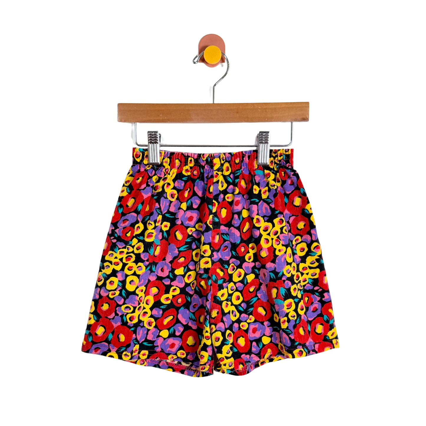 Colorful patterned shorts on a hanger against a white background