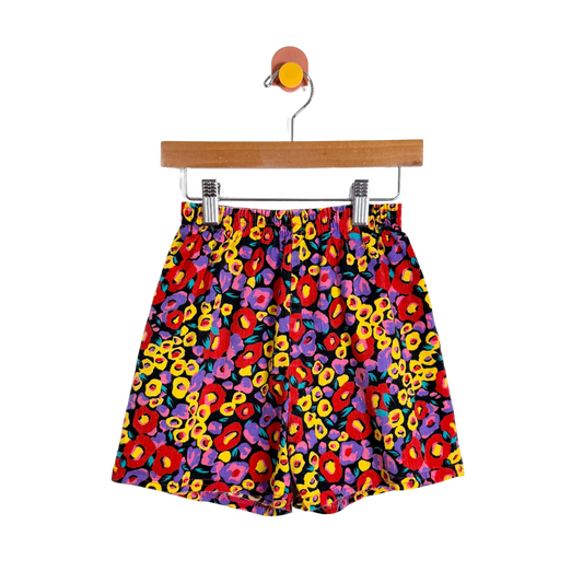 Colorful patterned shorts on a hanger against a white background