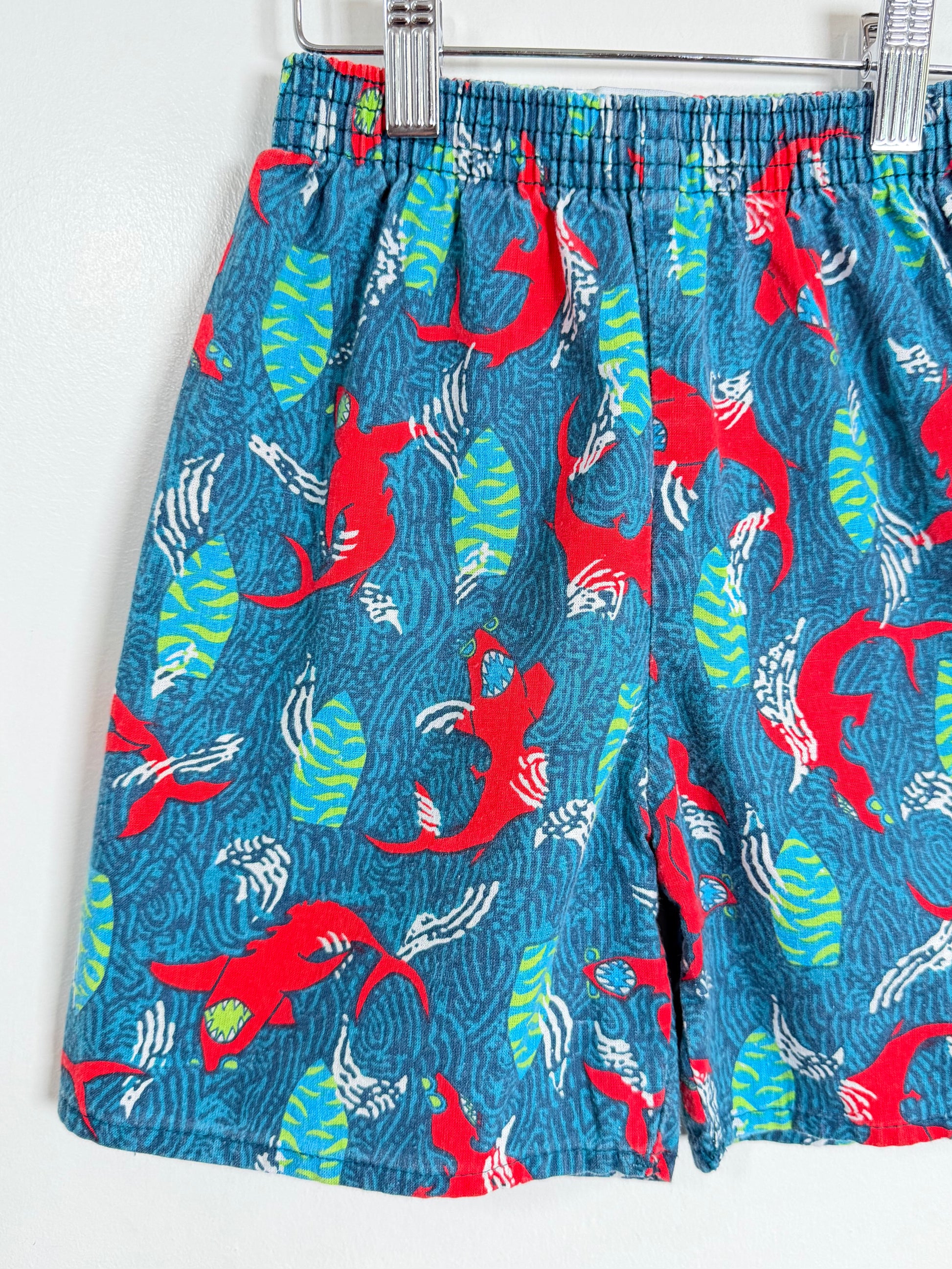 Blue shorts with red and green fish pattern on a white background