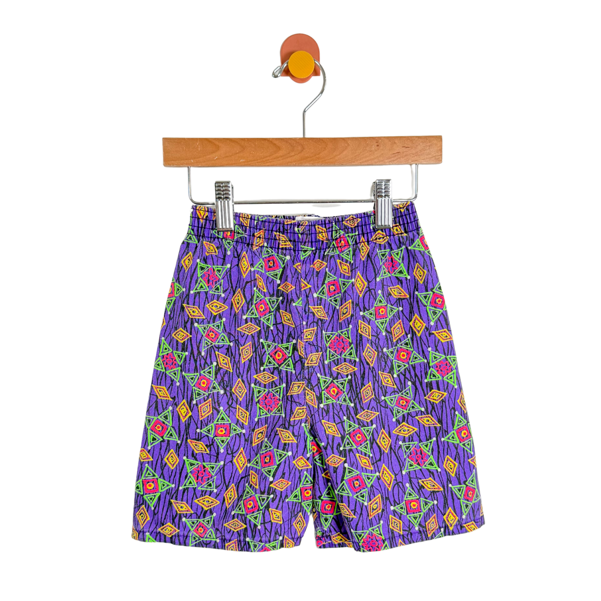 Colorful patterned shorts on a wooden hanger against a white background