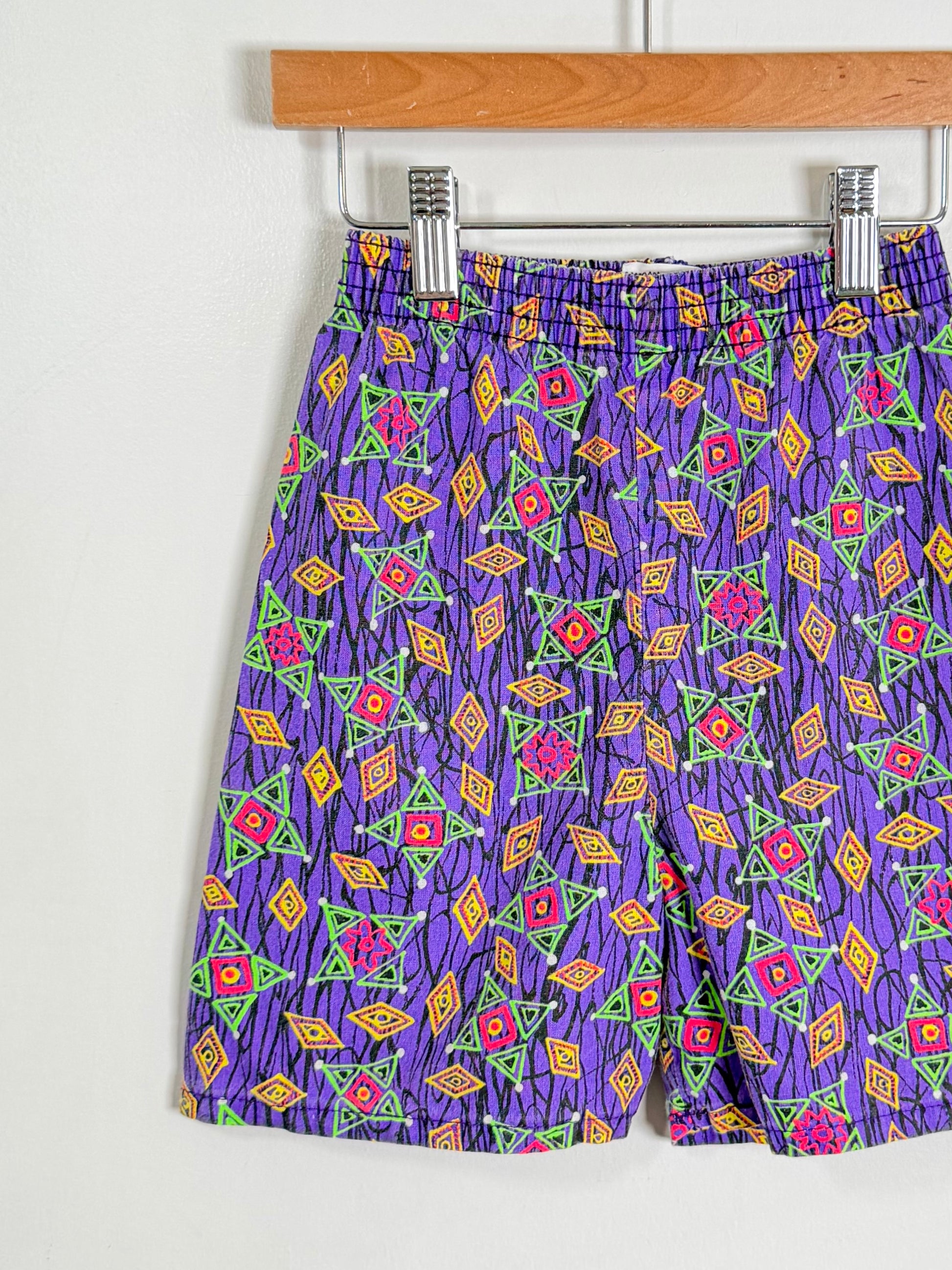 Colorful patterned shorts on a hanger against a white background