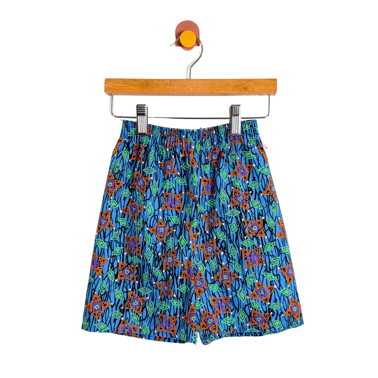 Colorful patterned shorts on a hanger against a white background