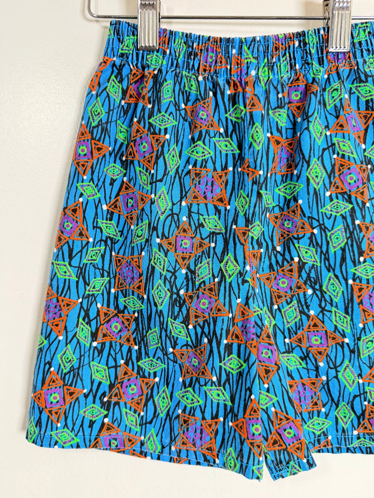 Colorful patterned shorts hanging on a rack against a white background