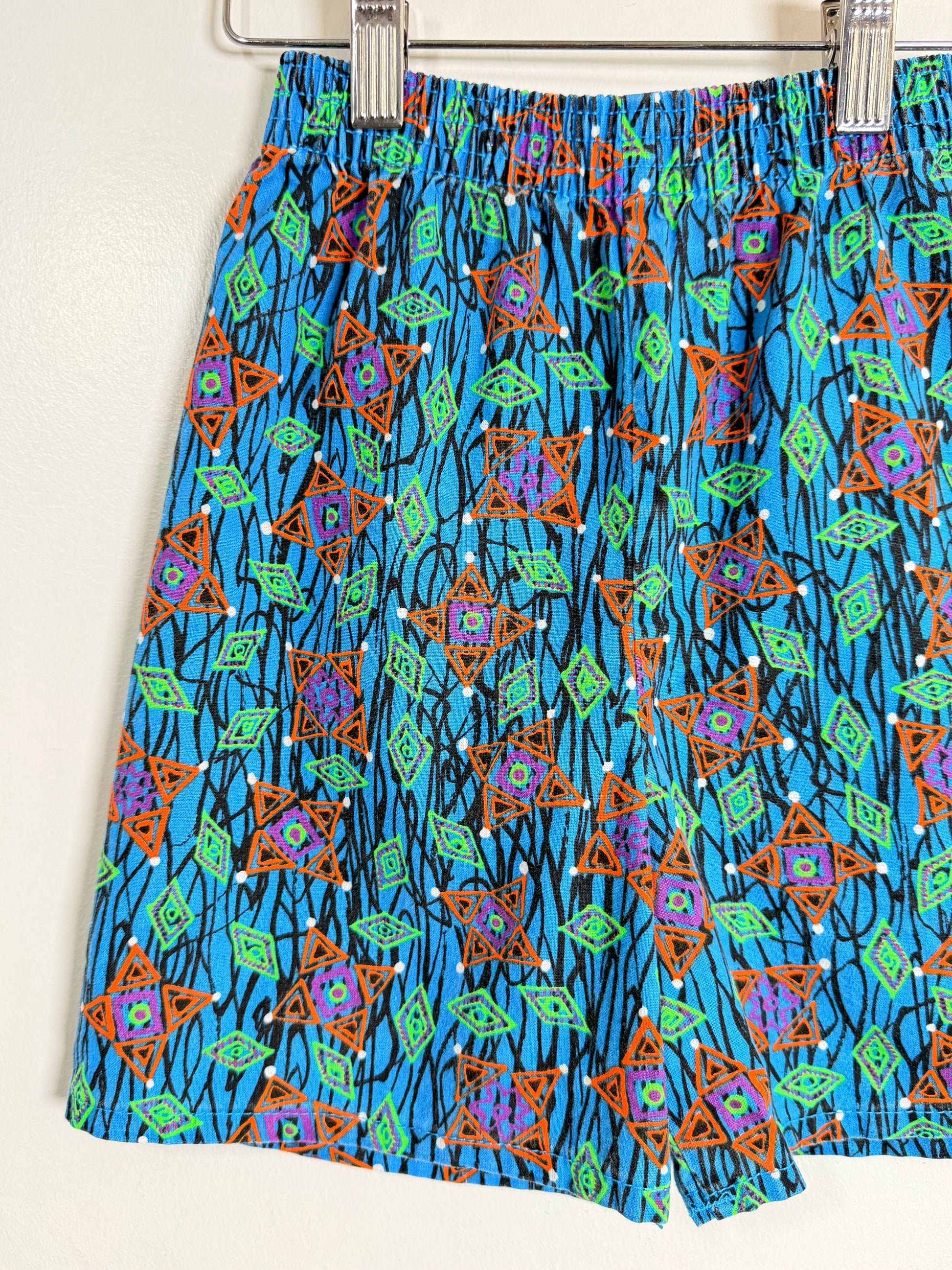 Colorful patterned shorts hanging on a rack against a white background