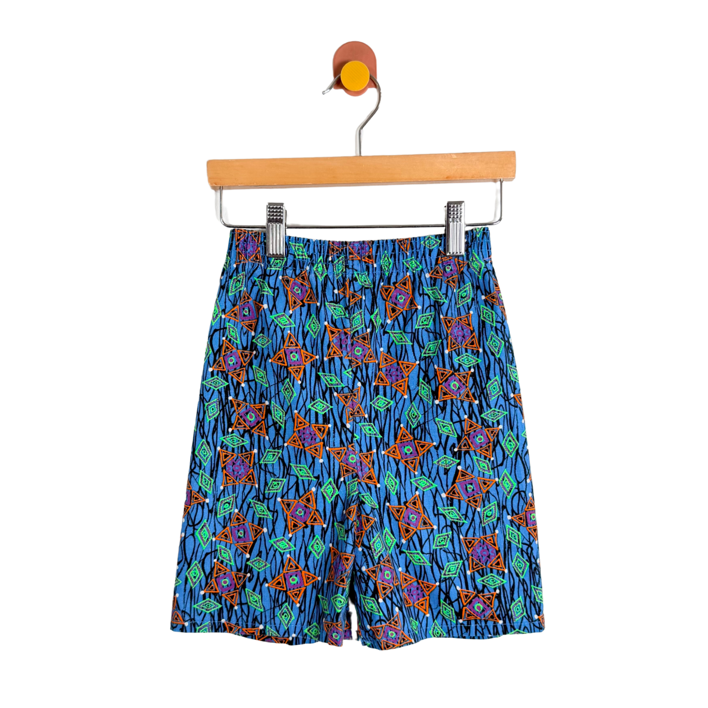 Colorful patterned shorts on a hanger against a white background