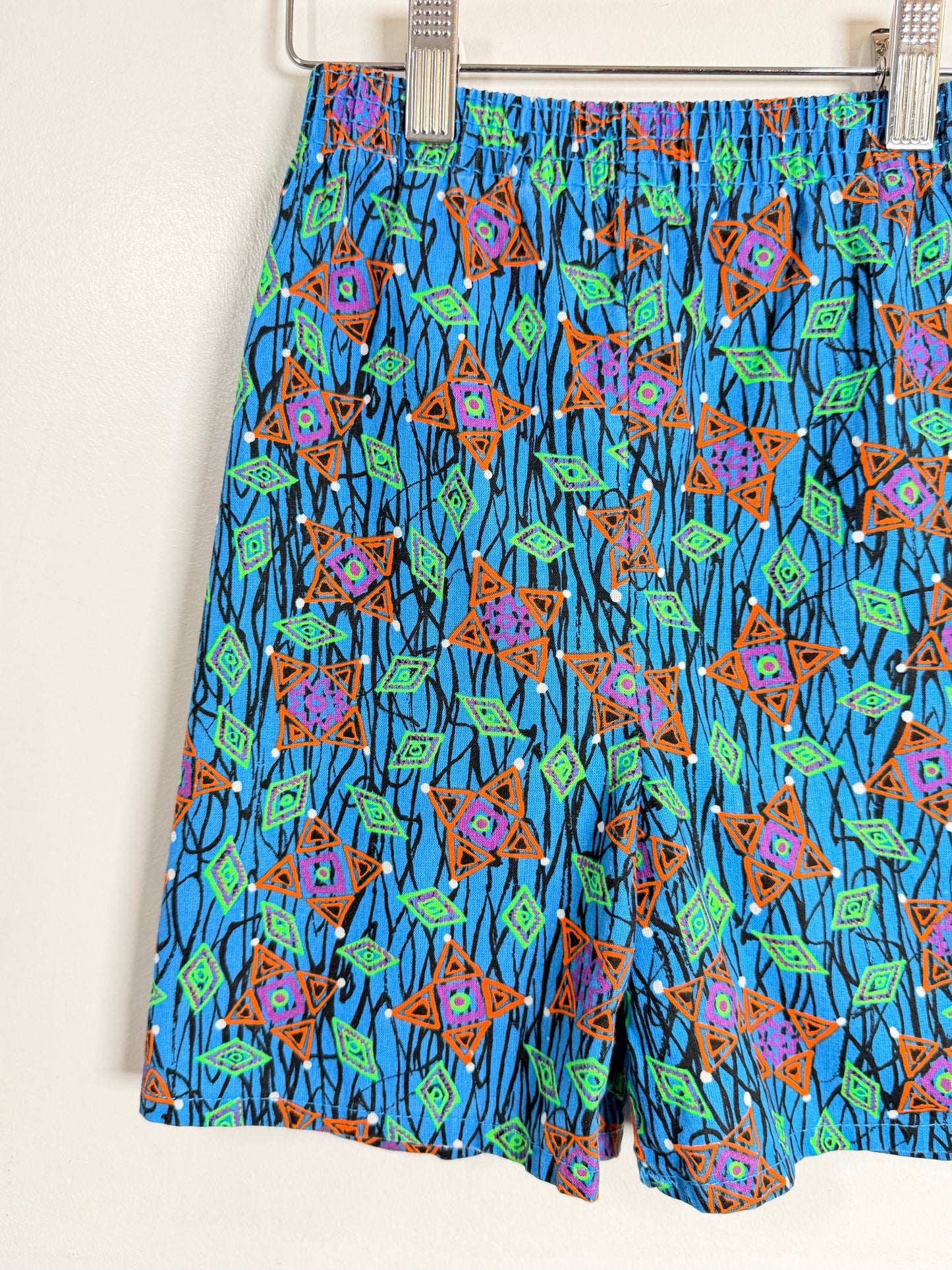 Colorful patterned shorts on a hanger against a white background