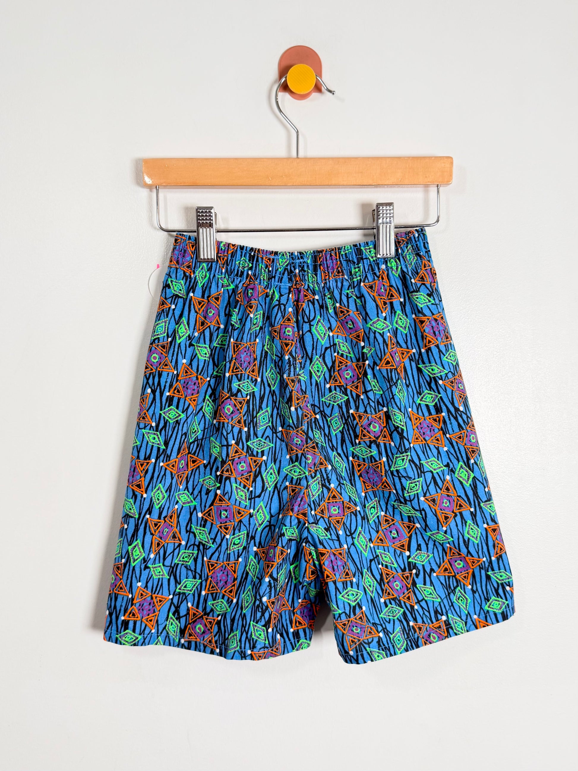 Blue patterned shorts on a hanger against a white background