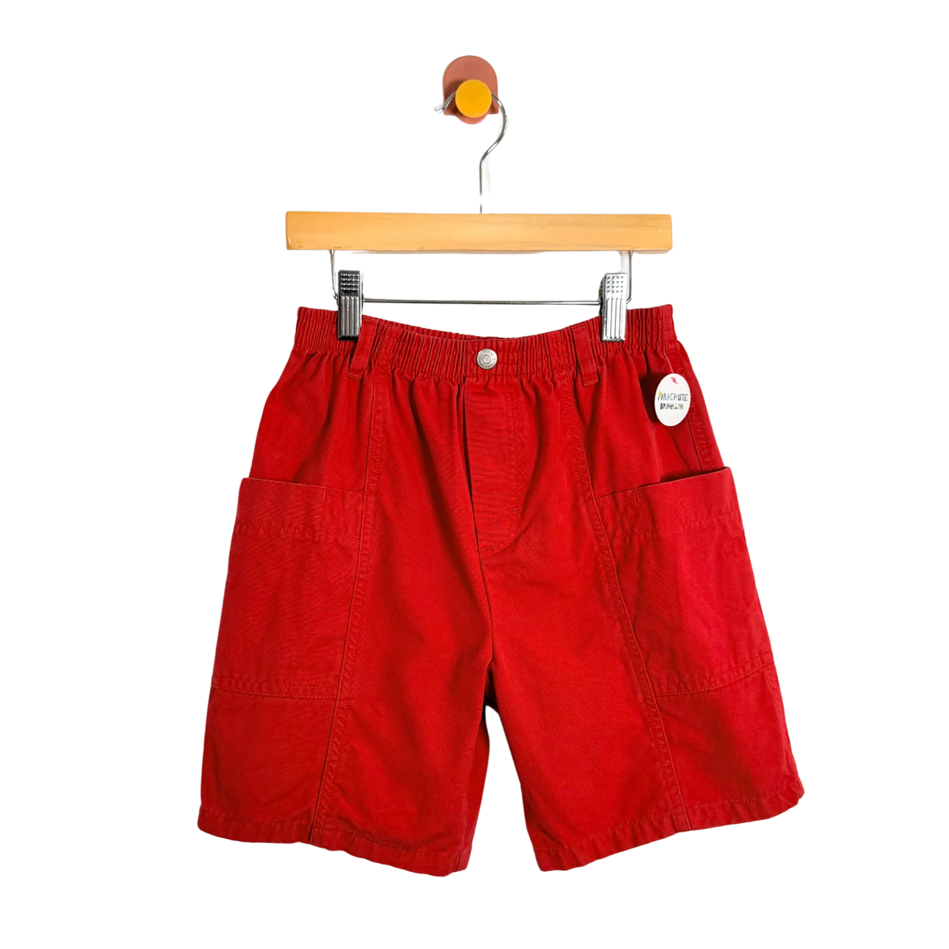 Red shorts on a wooden hanger against a white background