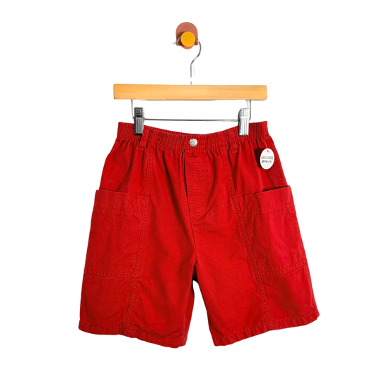 Red shorts on a wooden hanger against a white background
