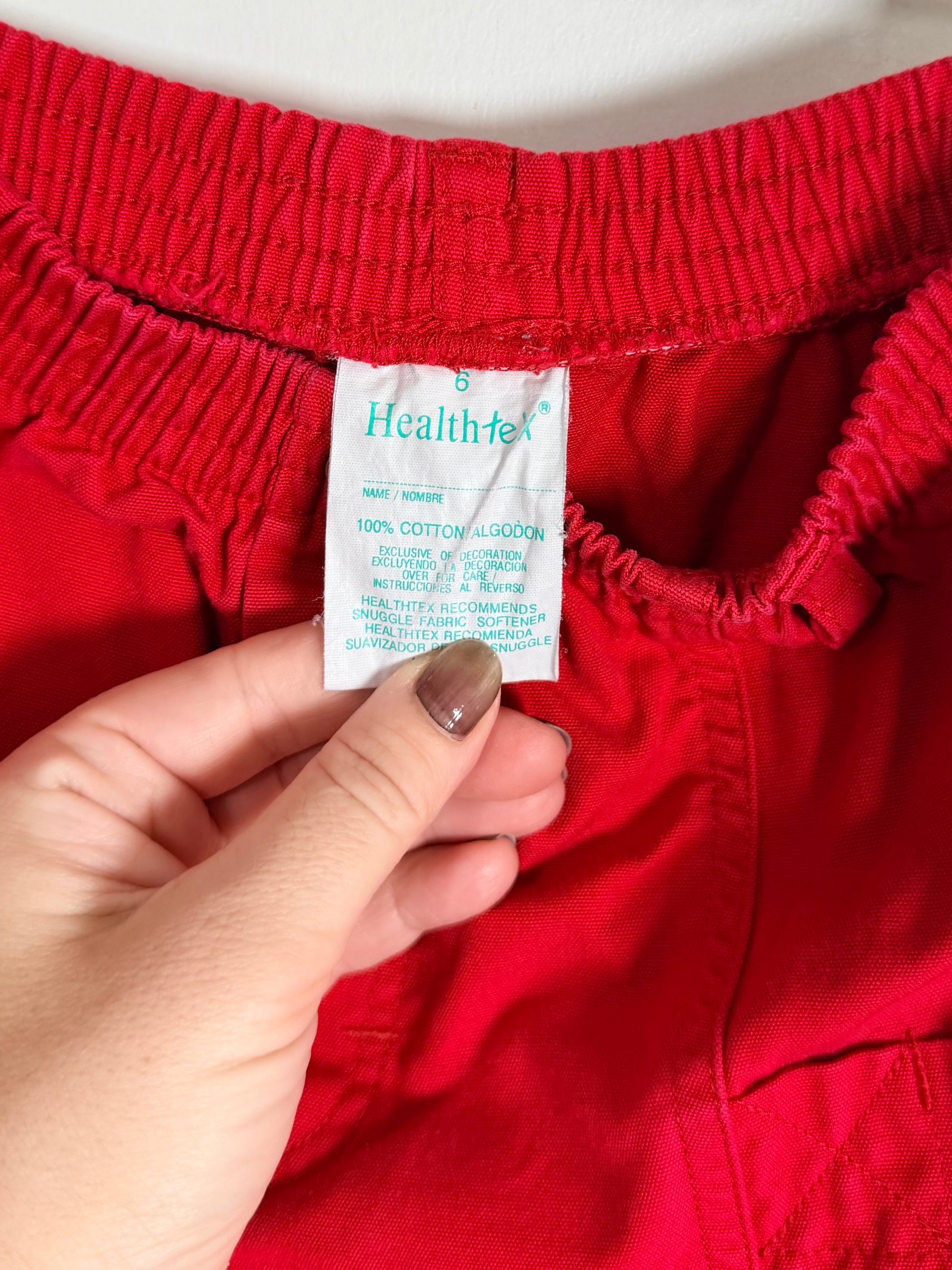 Red shorts with a visible brand label held by a hand against a white background