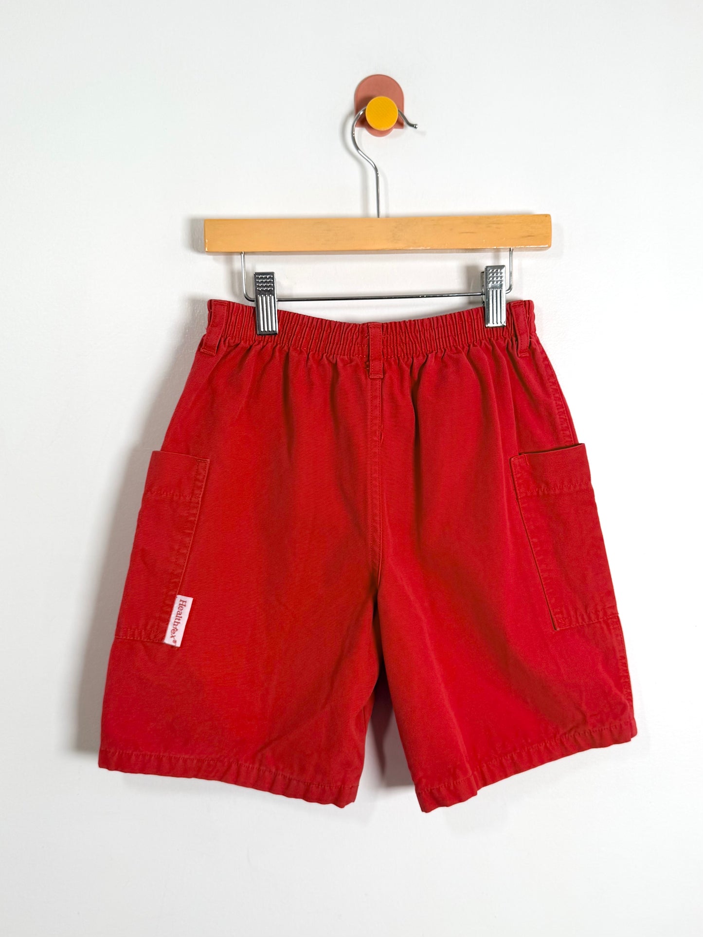 Red shorts on a hanger against a white background