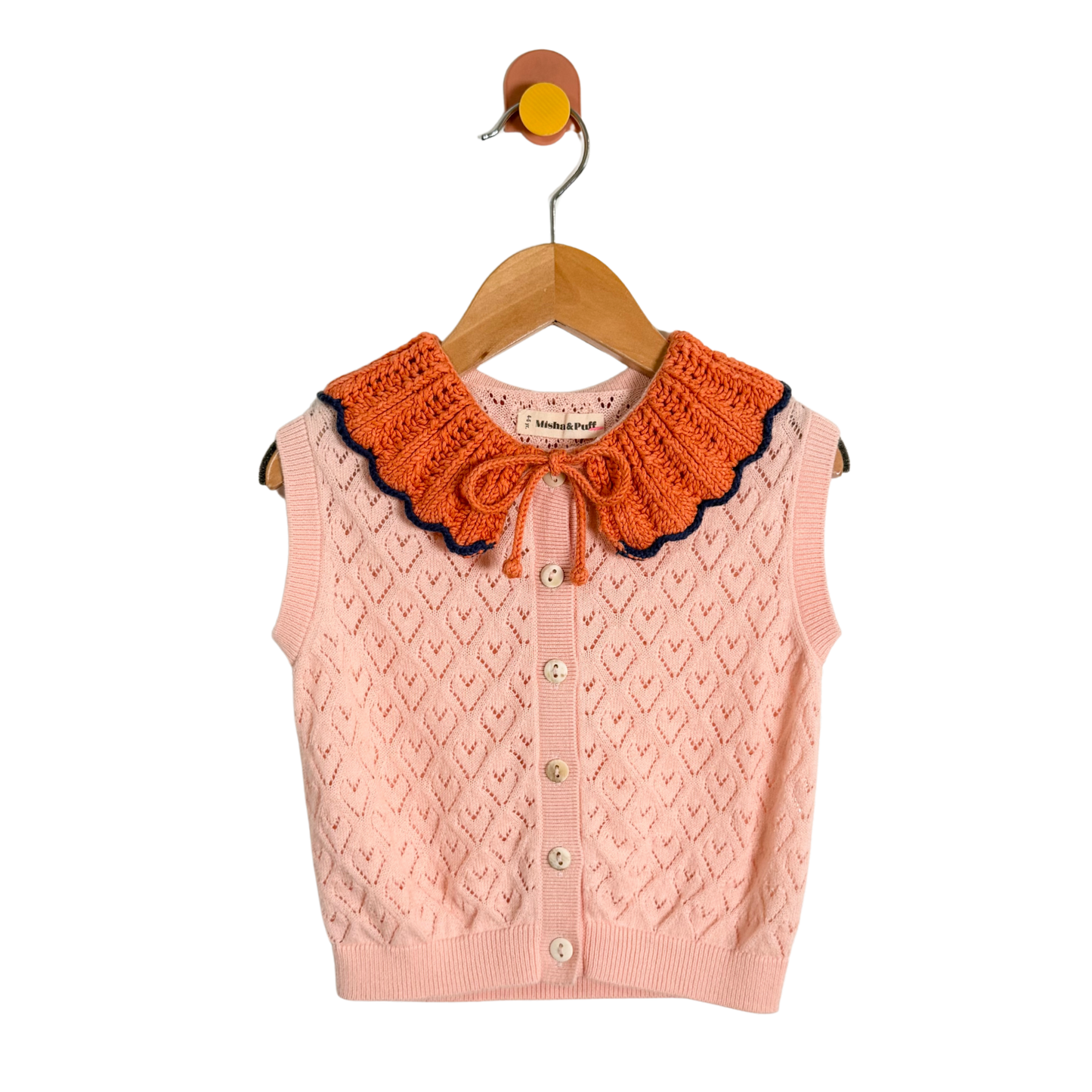 Pink knitted vest with orange collar on a hanger against a white background