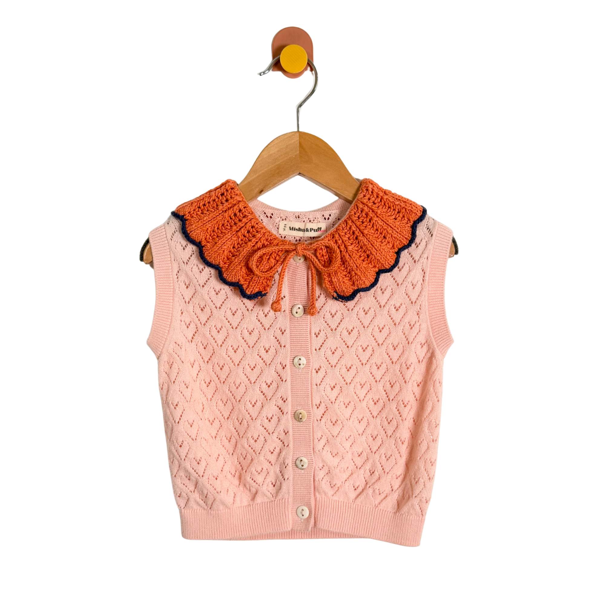 Pink knitted vest with orange collar on a hanger against a white background