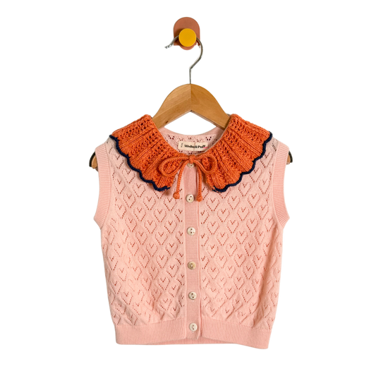 Pink knitted vest with orange collar on a hanger against a white background