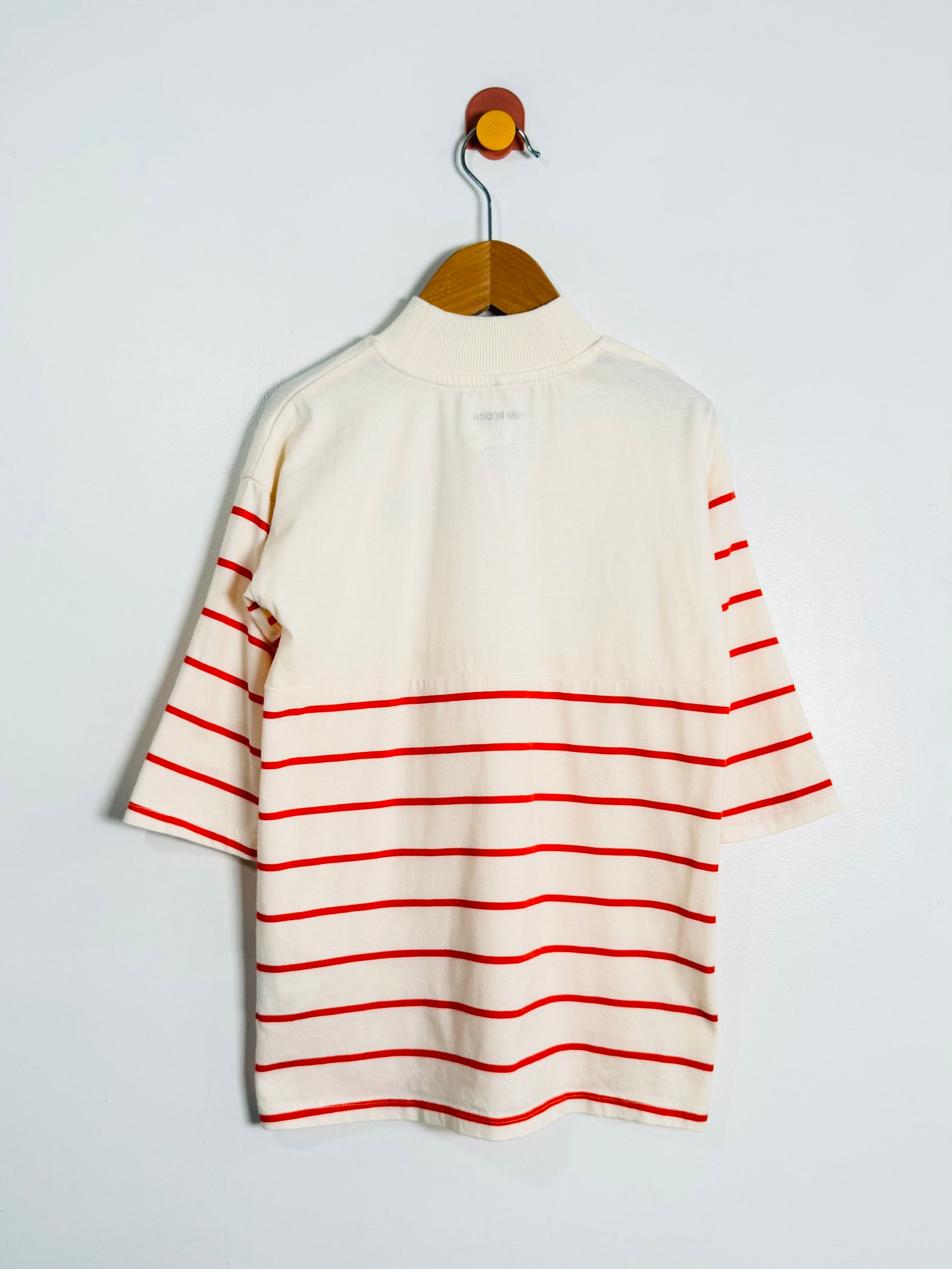 White dress with red stripes on a hanger against a light gray background
