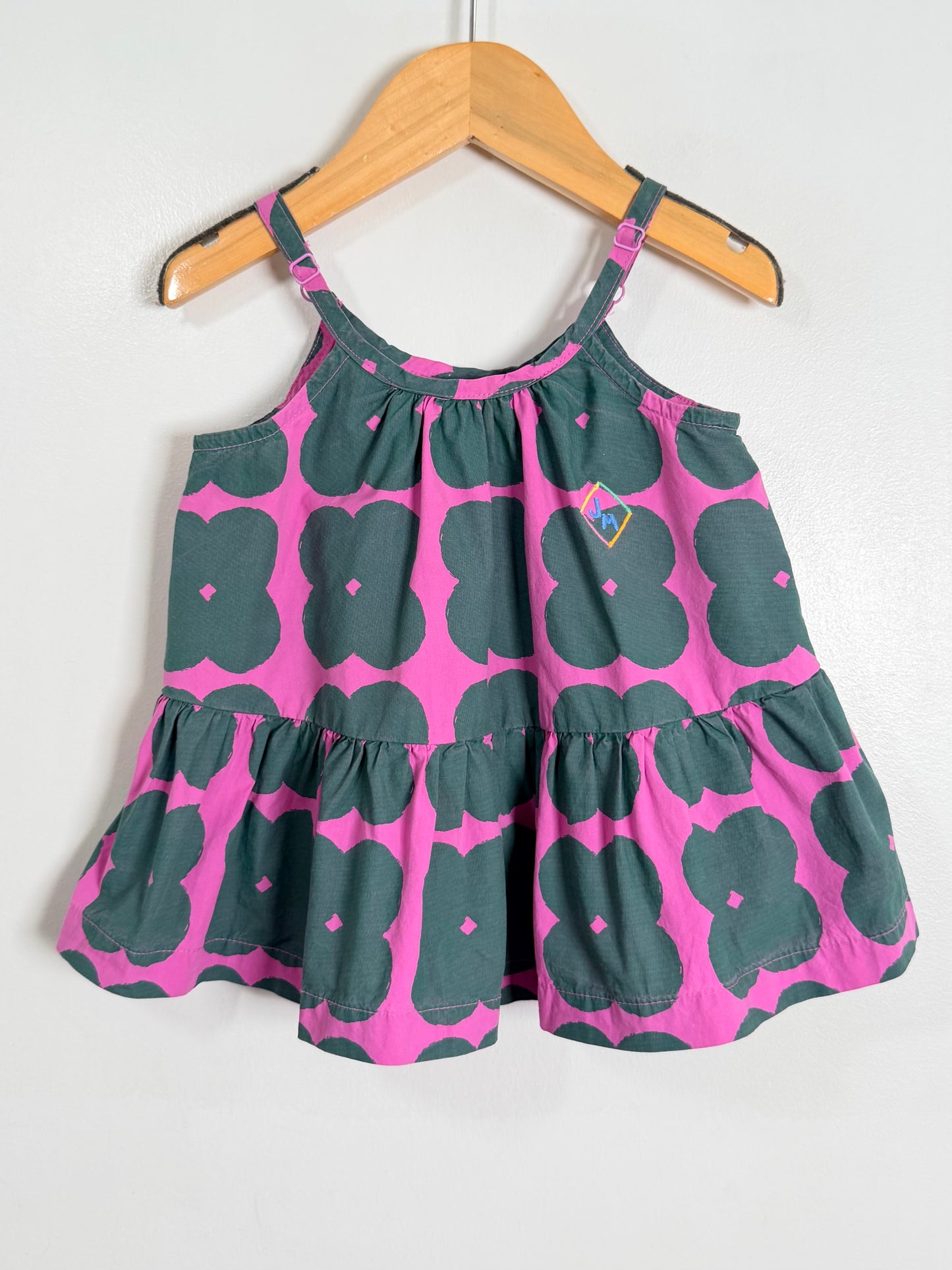 Children's dress with pink and green floral pattern on a hanger against a white background