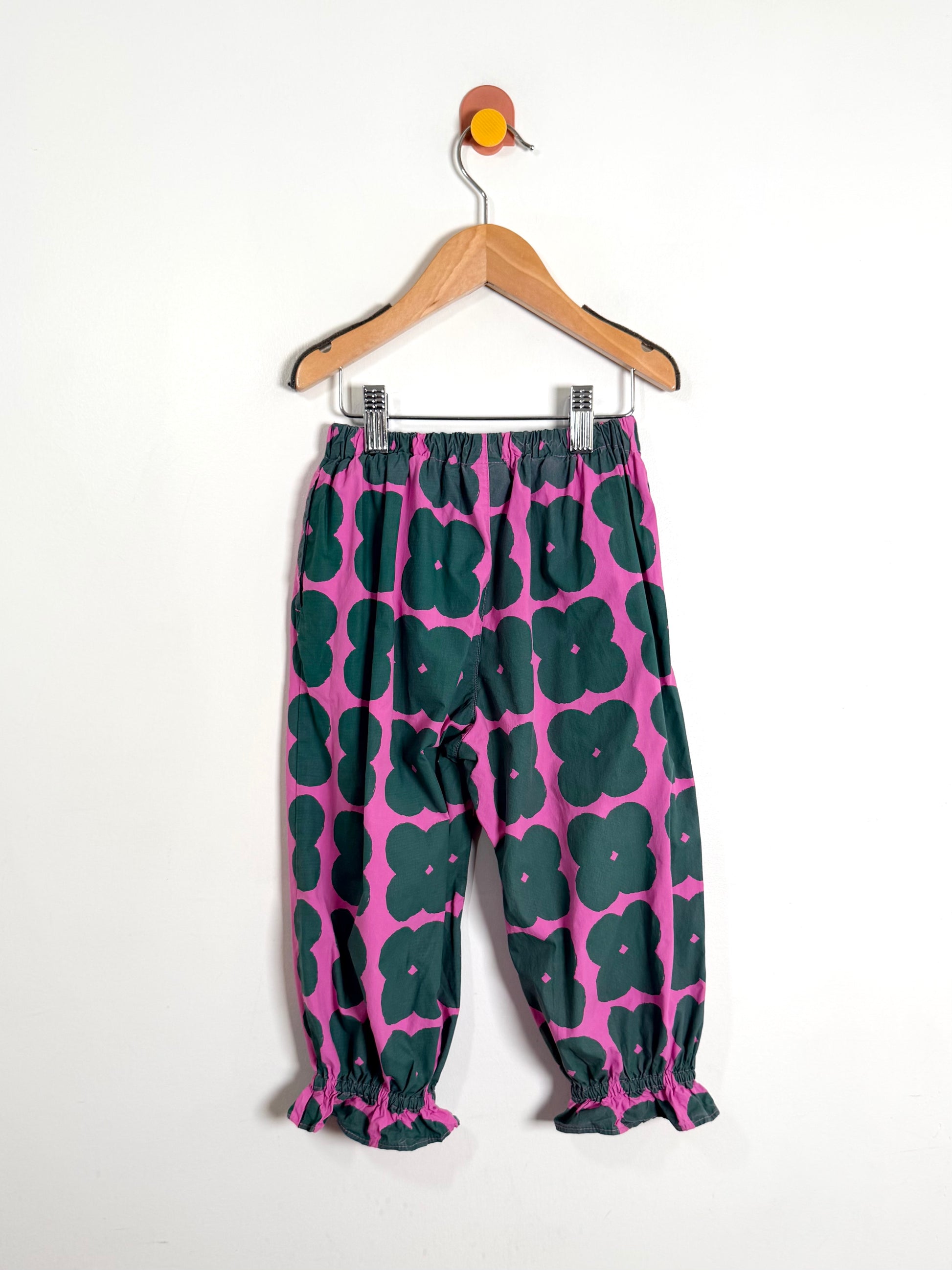Floral-patterned pants on a hanger against a white background