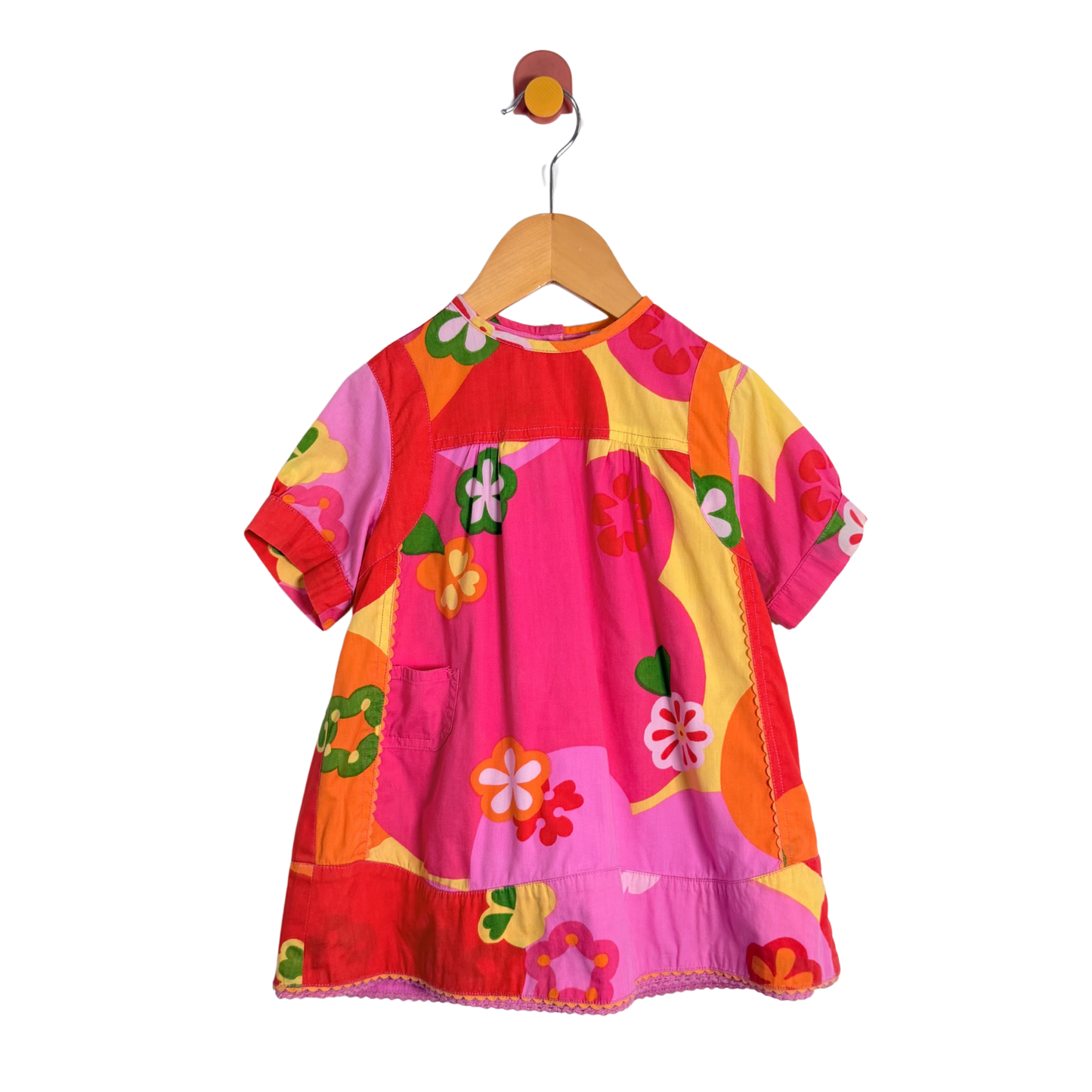 Colorful children's dress on a hanger against a white background