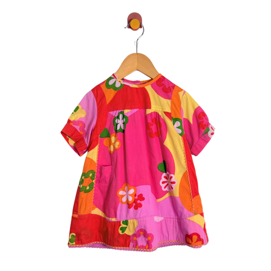 Colorful children's dress on a hanger against a white background