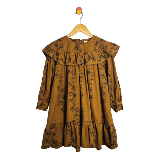 Mustard yellow dress with floral pattern on a hanger against a white background