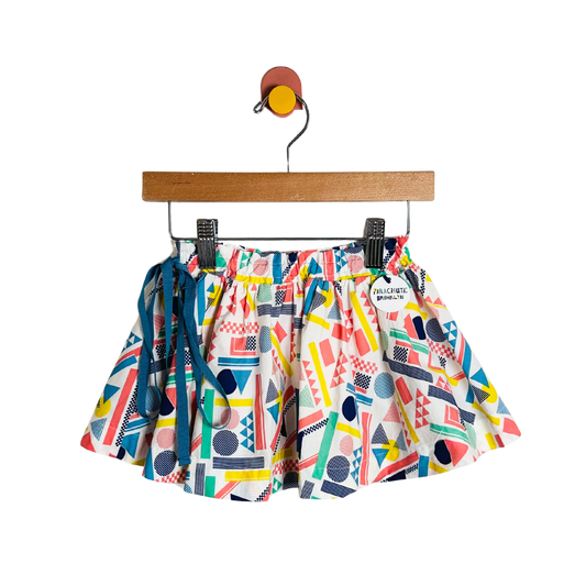 Colorful geometric-patterned shorts on a hanger against a white background