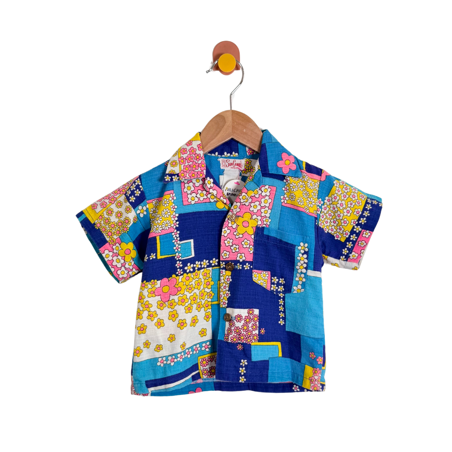 Colorful patchwork shirt on a hanger against a white background