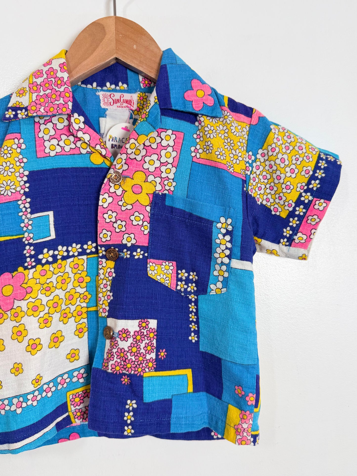 Colorful patterned shirt on a wooden hanger against a white background