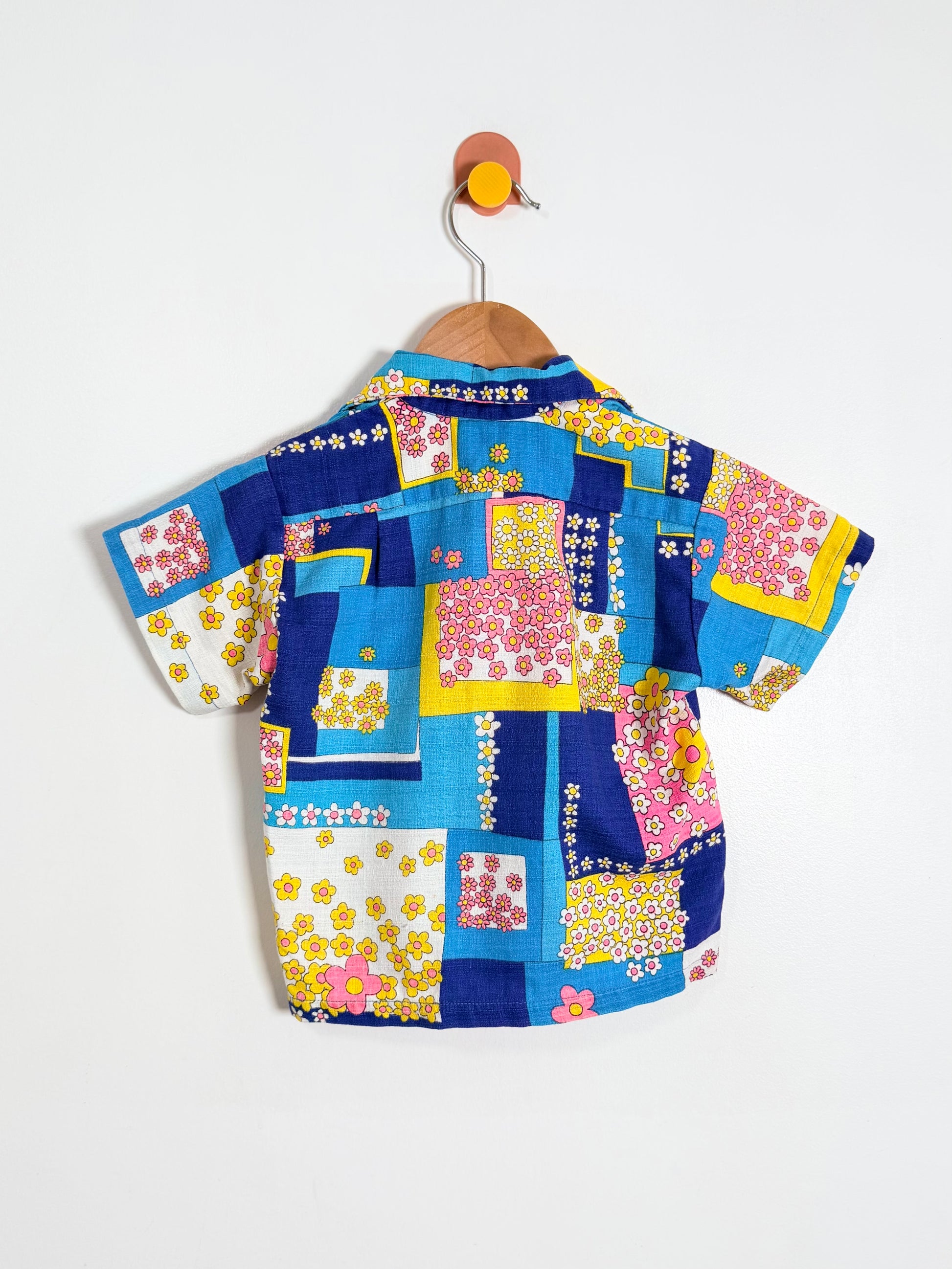 Colorful patchwork shirt on a hanger against a white background