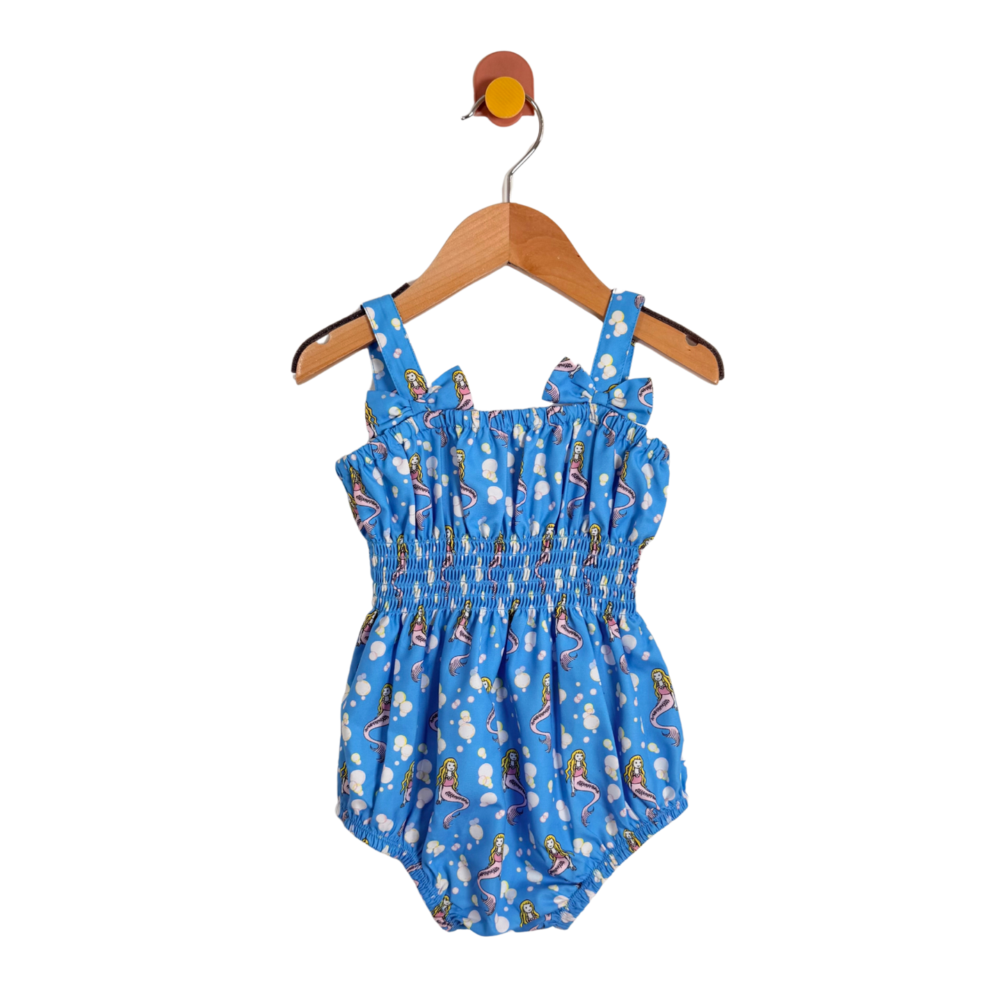 Blue children's romper with cartoon print on a wooden hanger against a white background