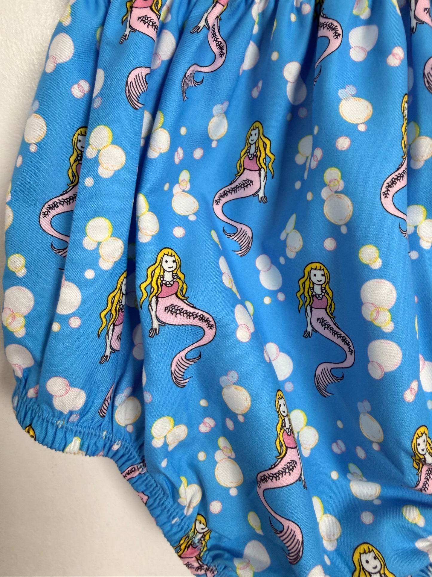 Blue swim trunks with mermaid pattern on a white surface