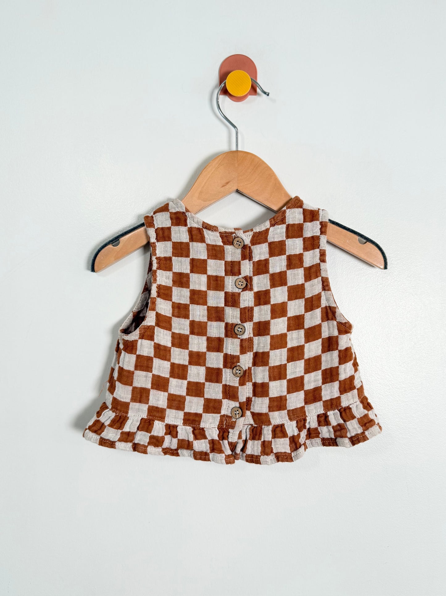 Checkered dress on a wooden hanger against a white background