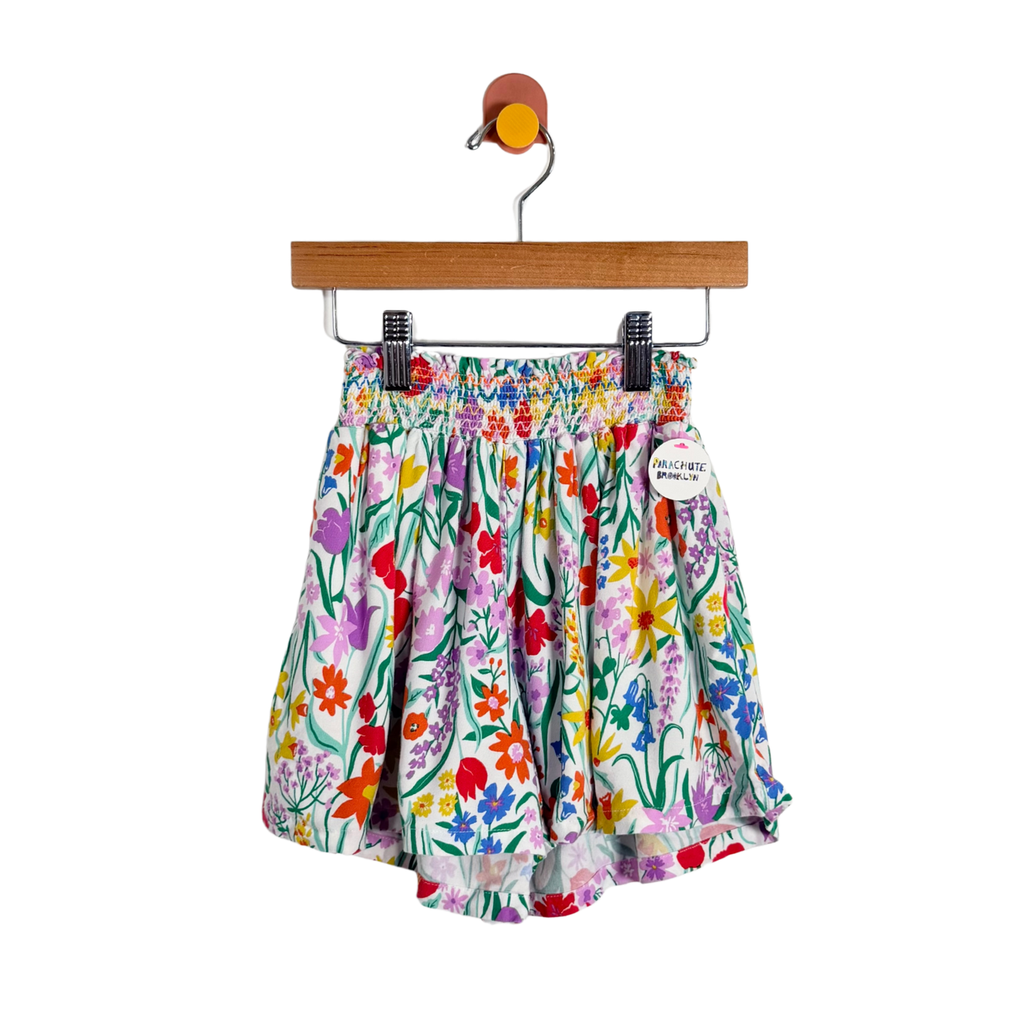 Colorful floral shorts on a hanger against a white background