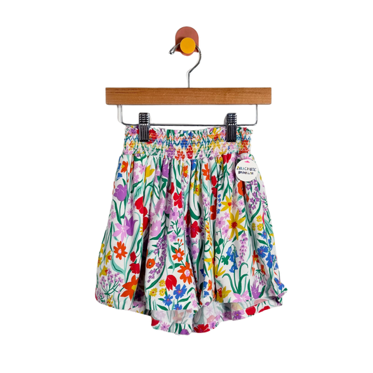 Colorful floral shorts on a hanger against a white background