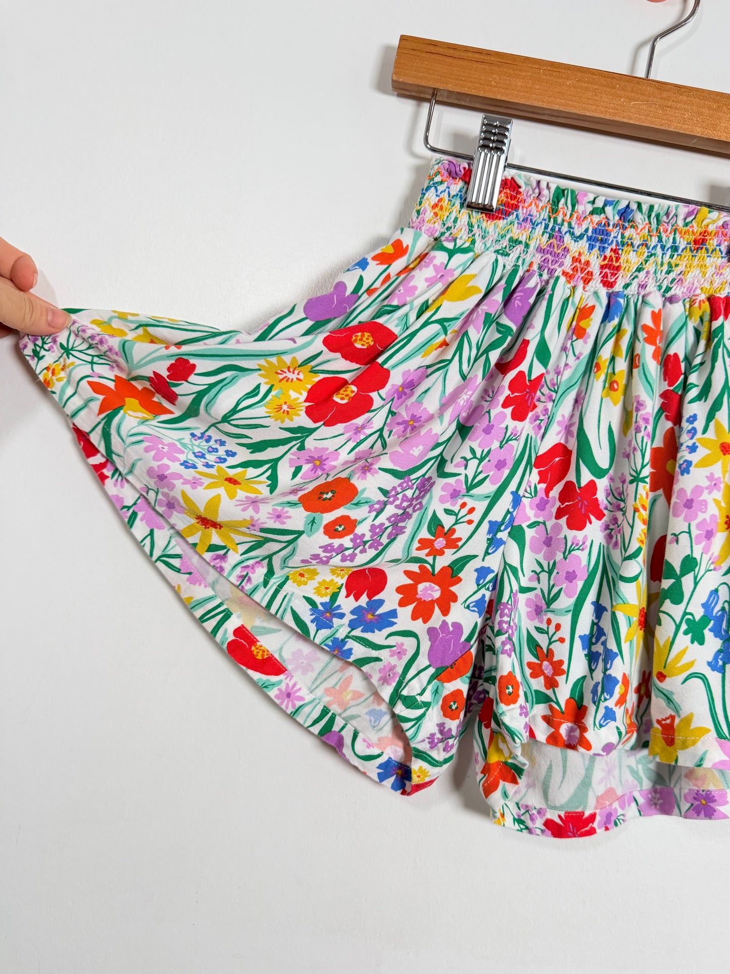 Colorful floral-patterned shorts on a hanger against a white background