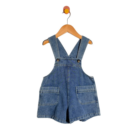 Blue denim overall dress on a wooden hanger against a white background