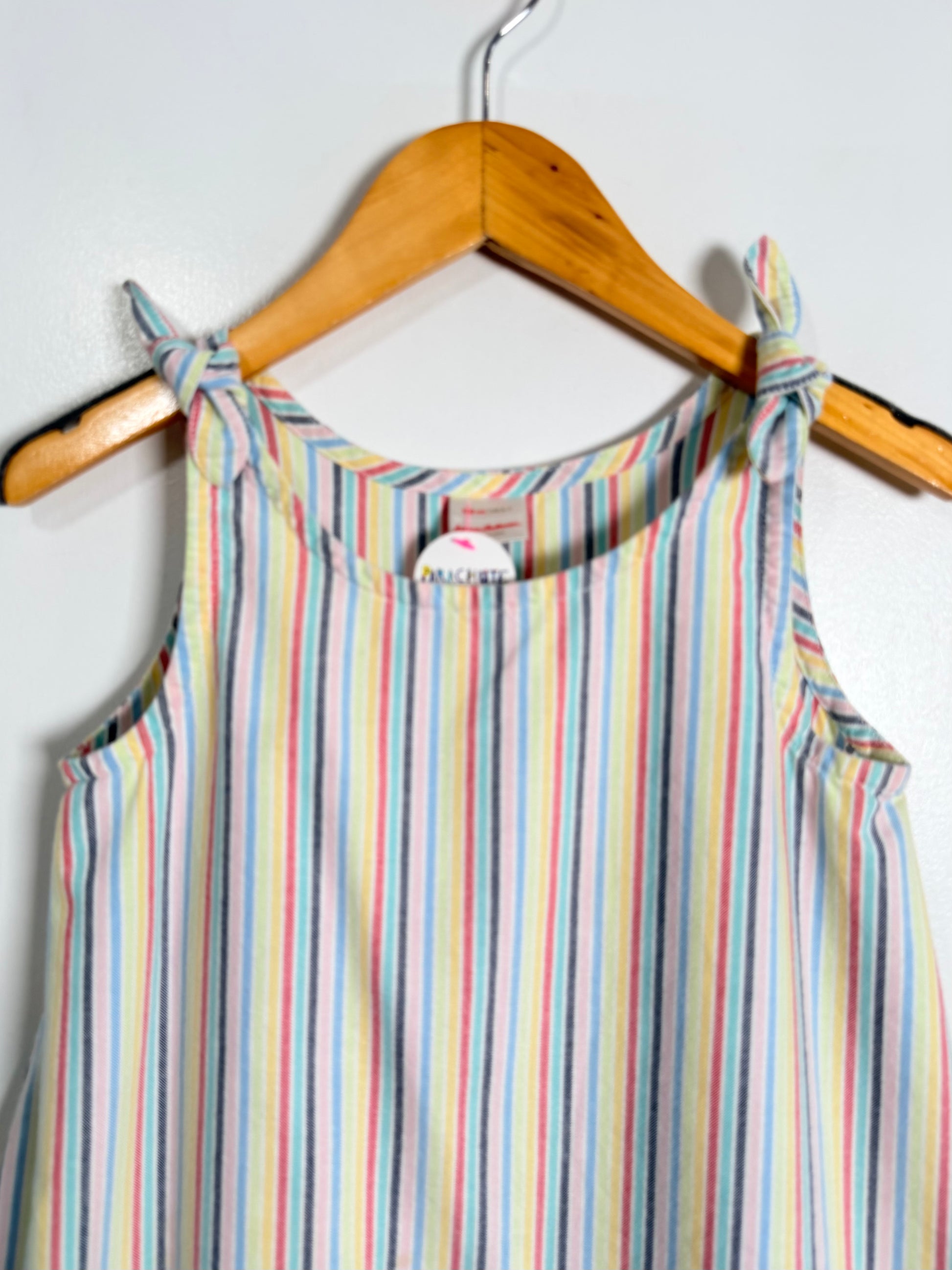 Multicolored striped dress on a wooden hanger against a white background