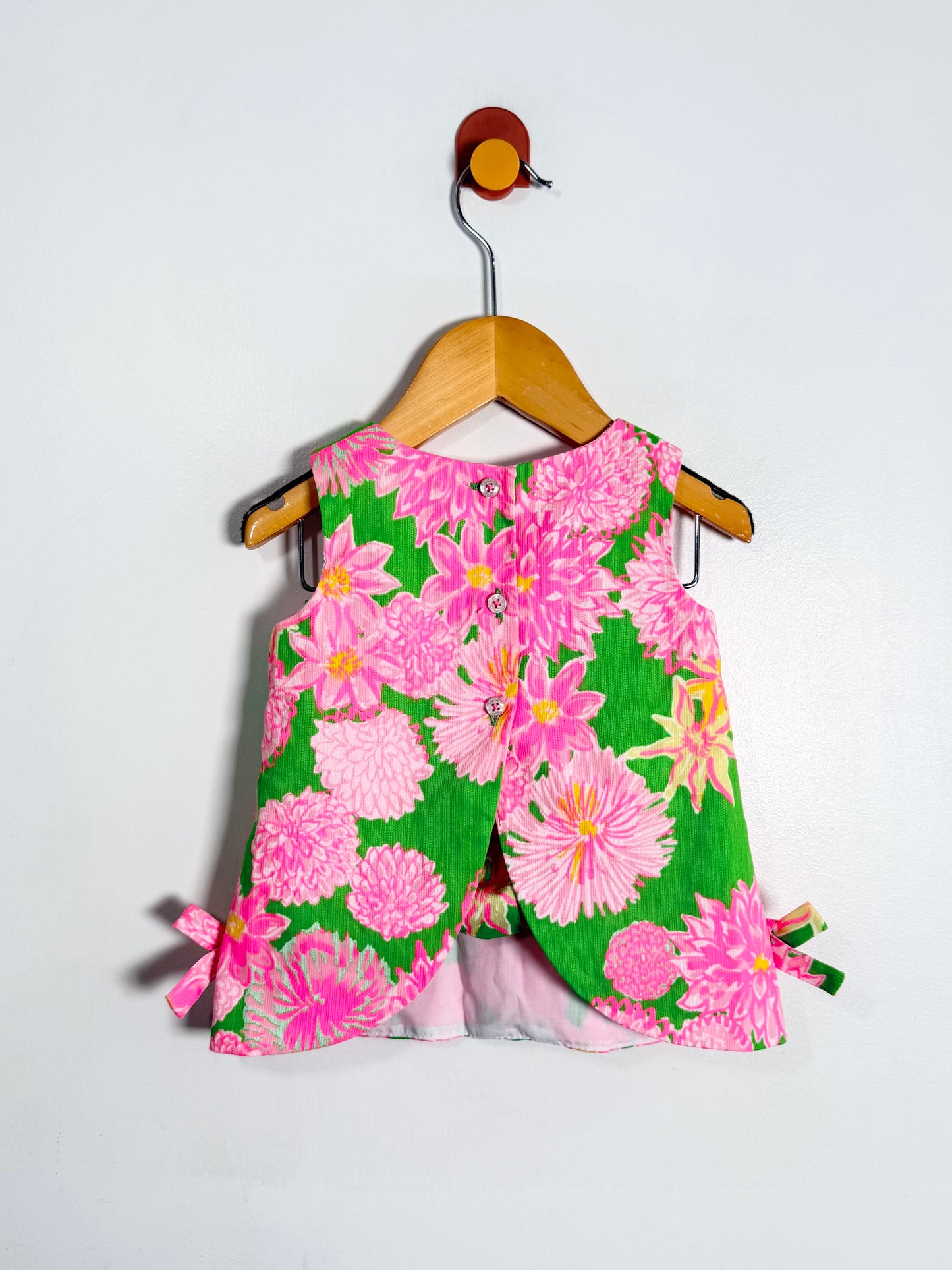 Floral dress with pink and green flowers on a hanger against a white background