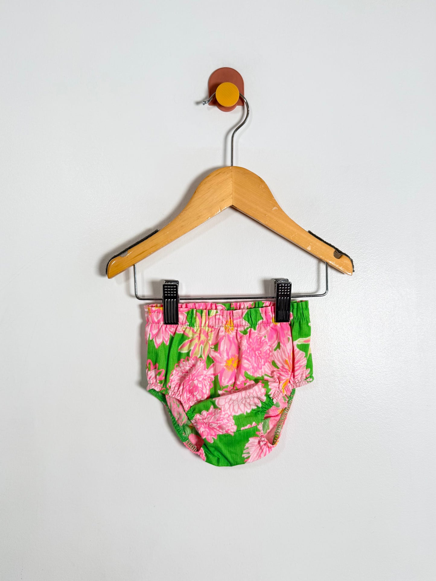 Floral-patterned baby bloomers on a hanger against a white background
