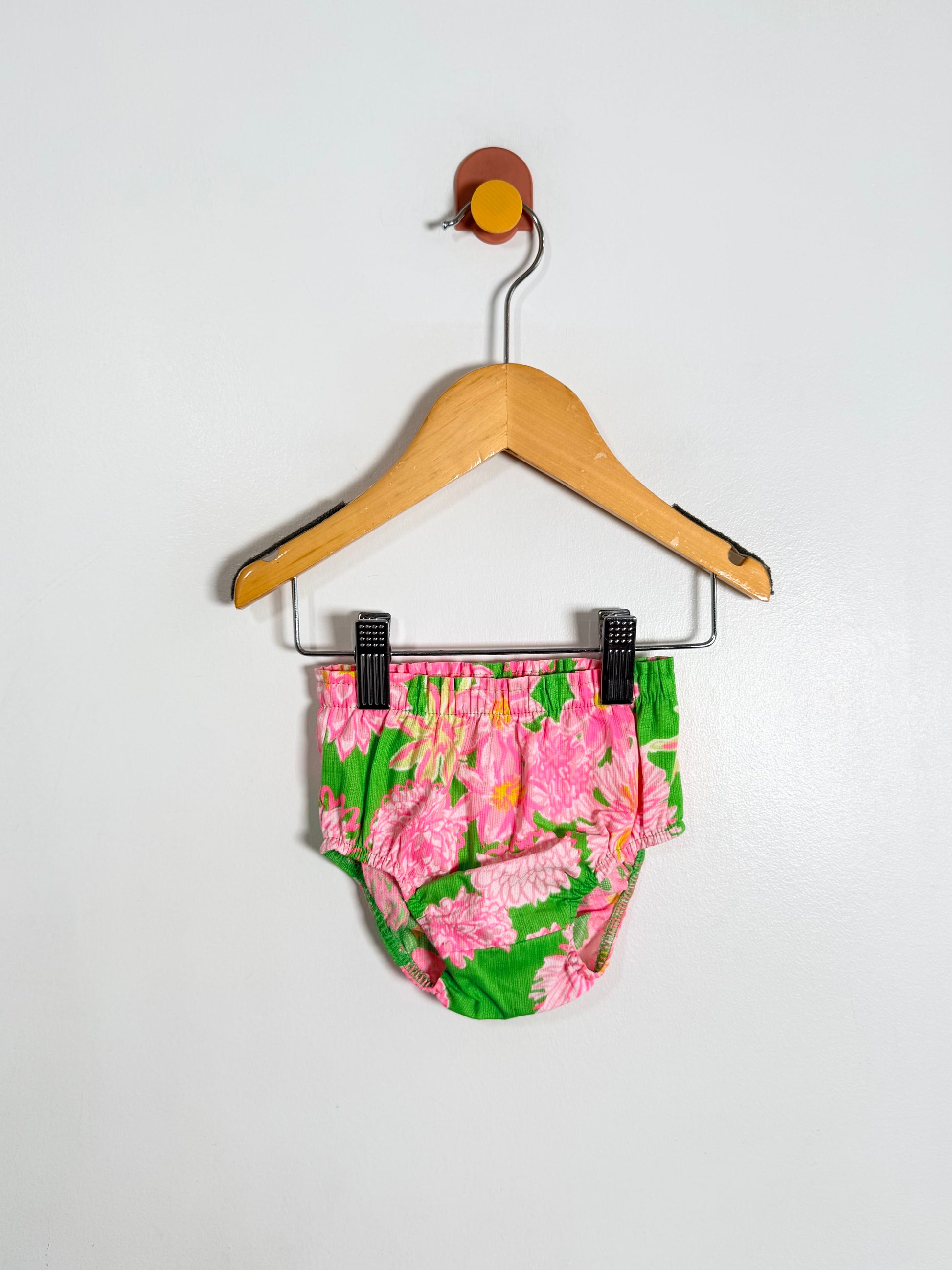 Floral-patterned baby bloomers on a hanger against a white background