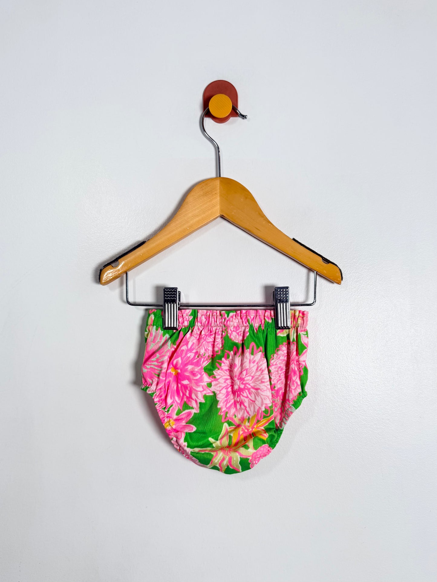 Floral-patterned shorts on a hanger against a white background