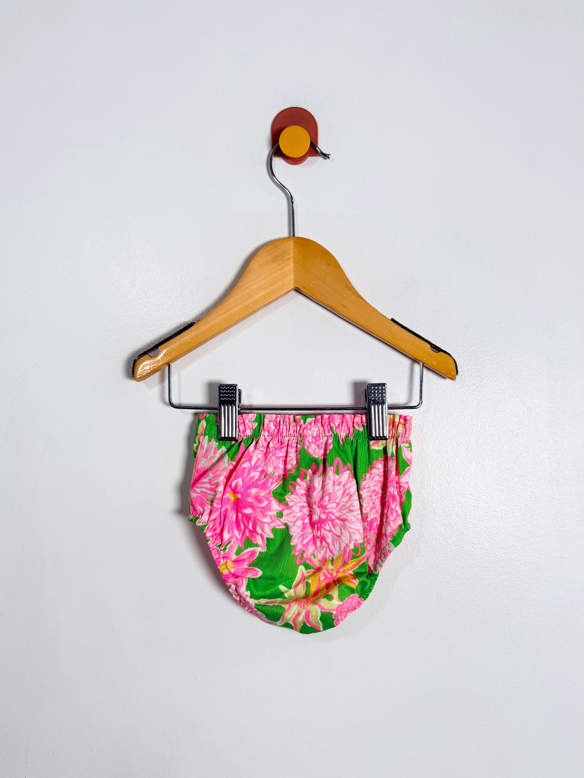 Floral-patterned shorts on a hanger against a white background