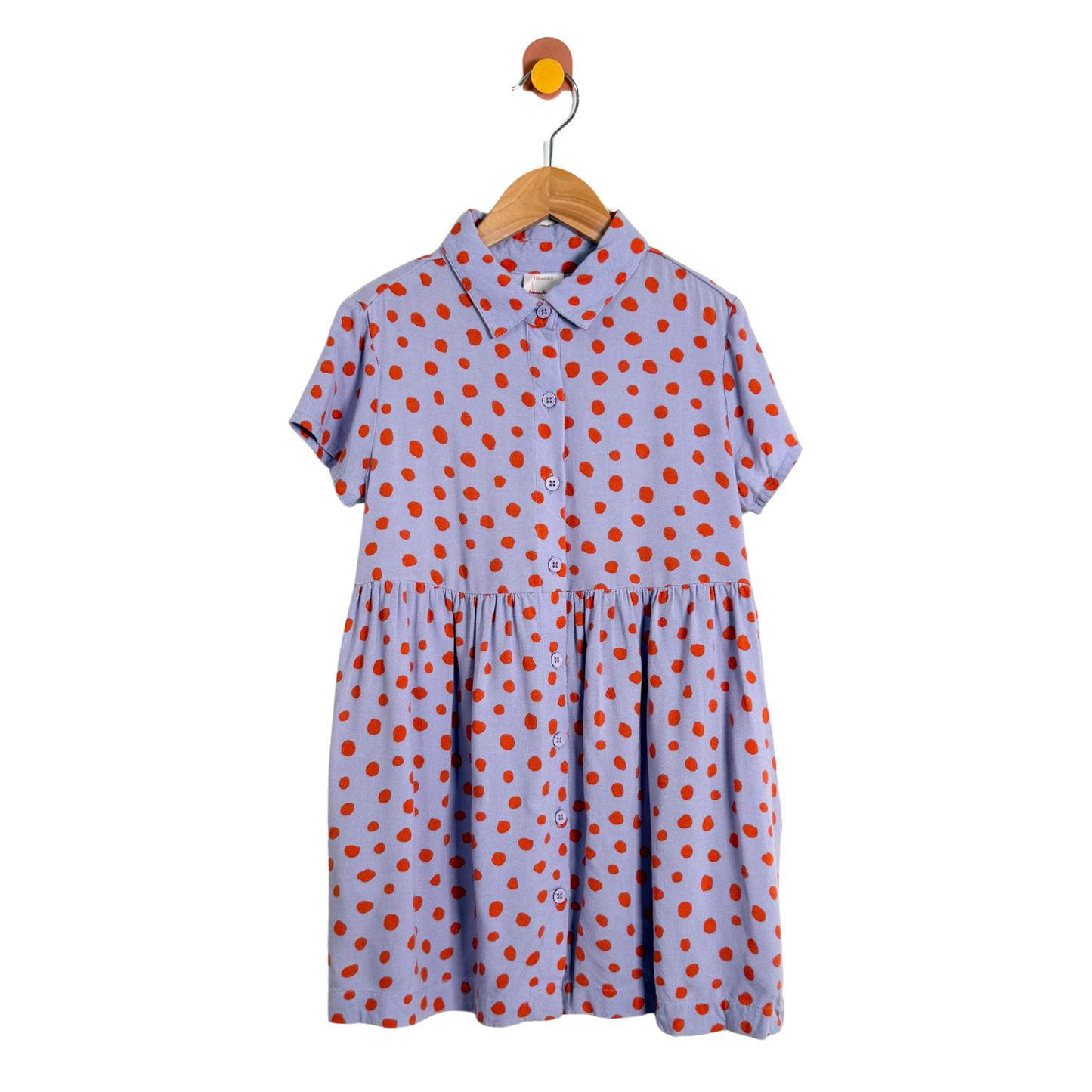 Purple dress with orange polka dots on a wooden hanger against a white background