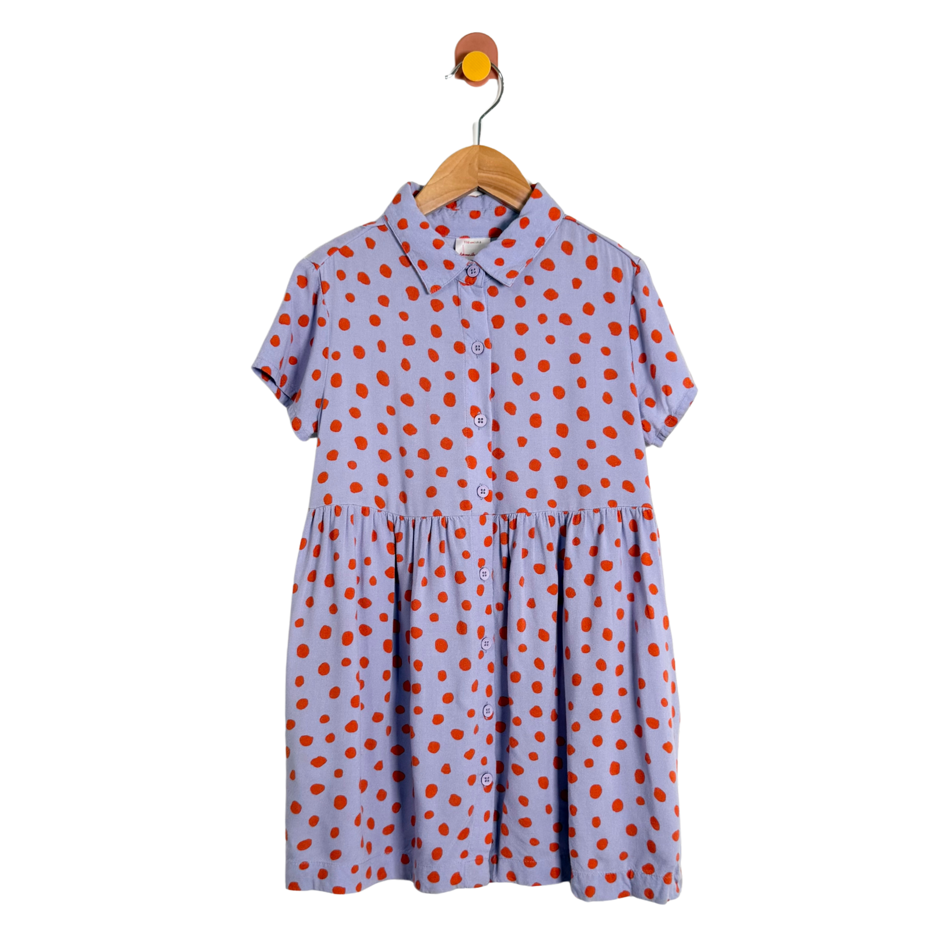 Purple dress with orange polka dots on a wooden hanger against a white background