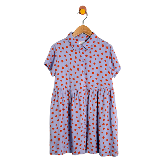 Purple dress with orange polka dots on a wooden hanger against a white background