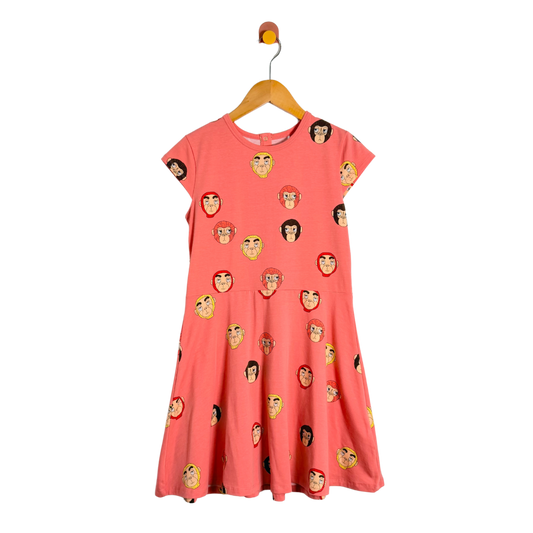 Coral dress with monkey face pattern on a hanger against a white background