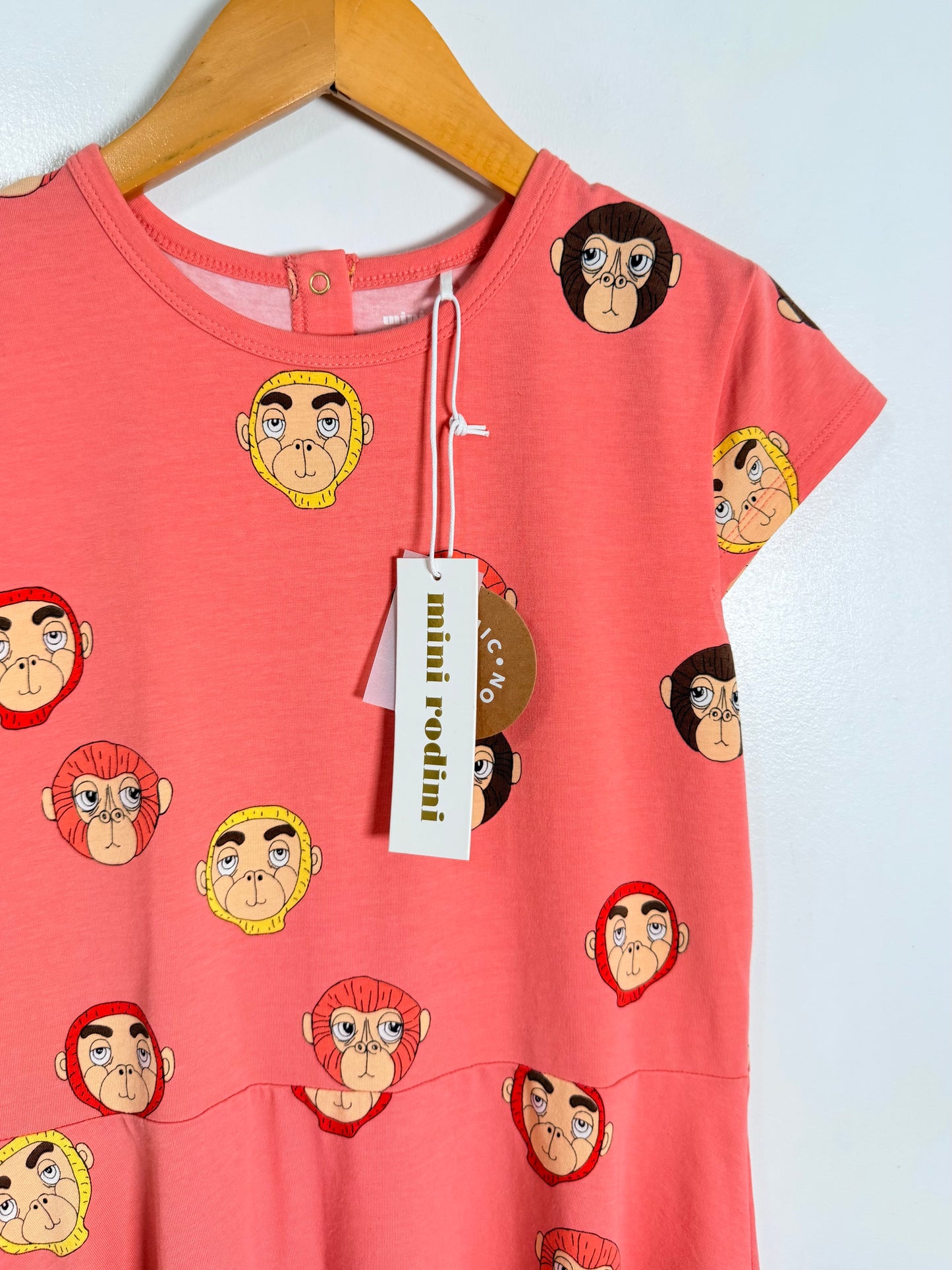 Pink dress with monkey print on a hanger against a white background