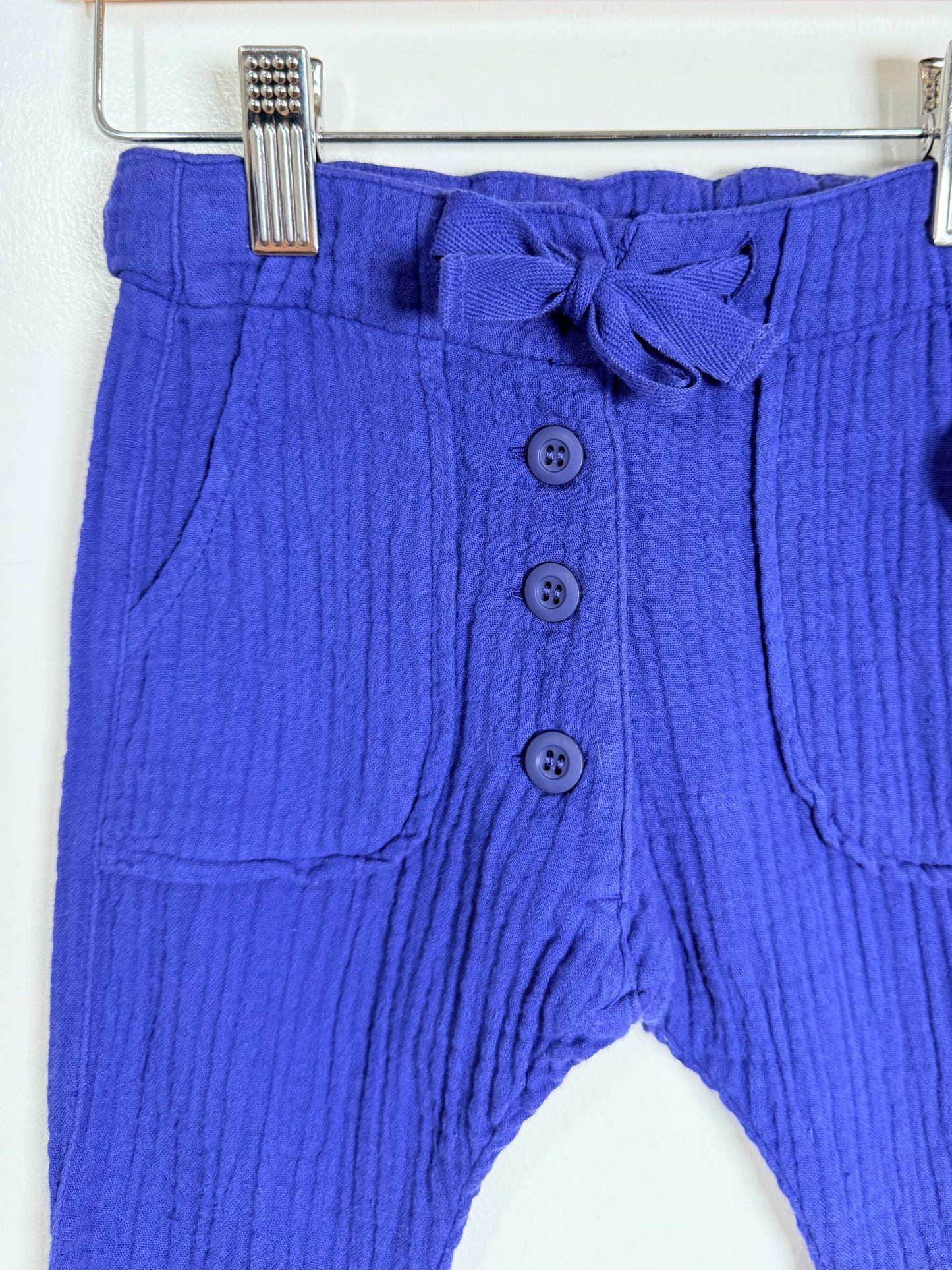 Blue gauzy pants with a bow and buttons on a white background