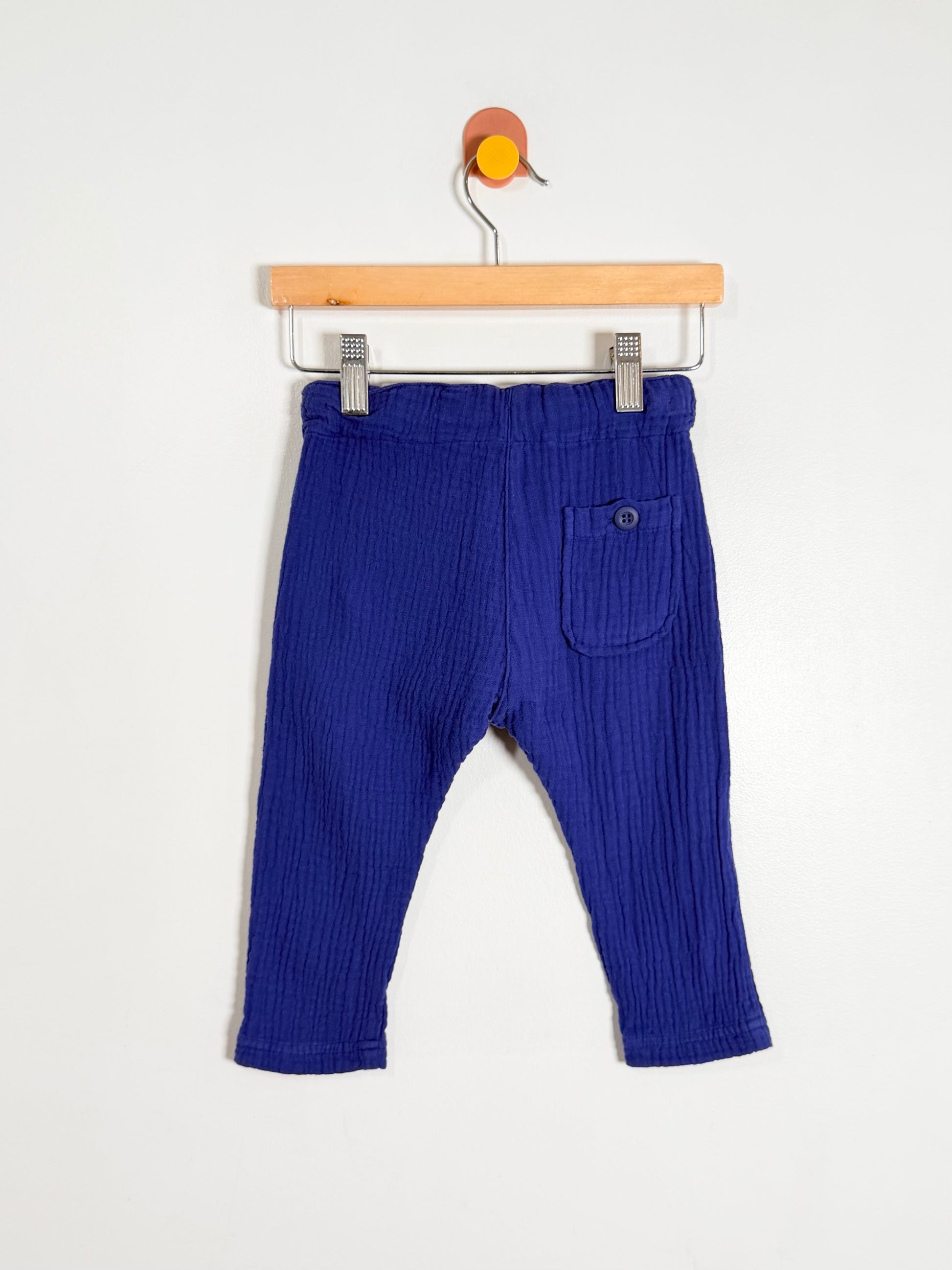 Blue baby pants on a wooden hanger against a white background