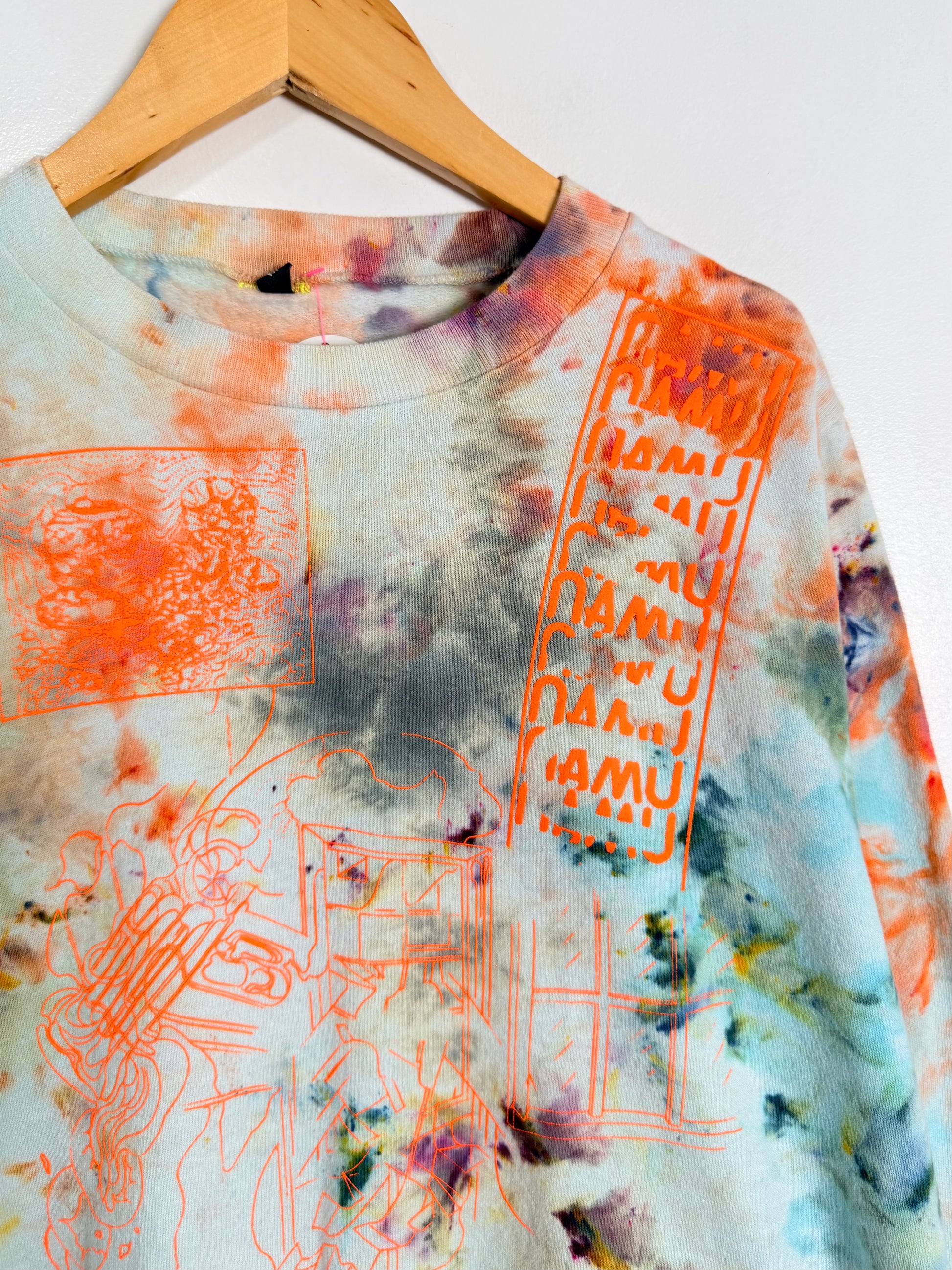 Tie-dye sweatshirt with orange graphics on a hanger against a white background