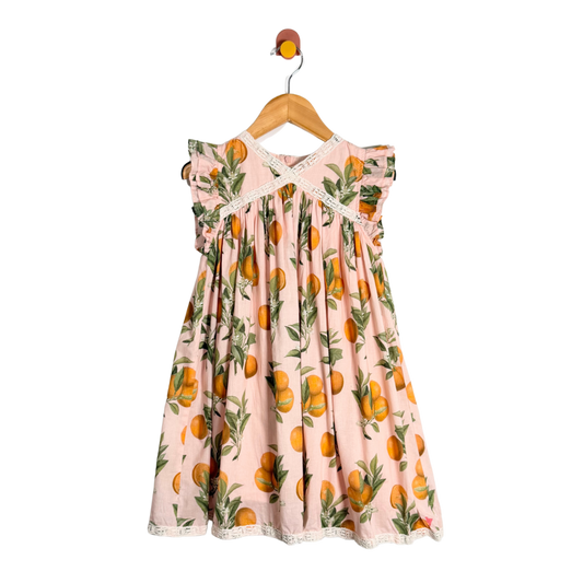 Pink dress with orange pattern on a hanger against a white background